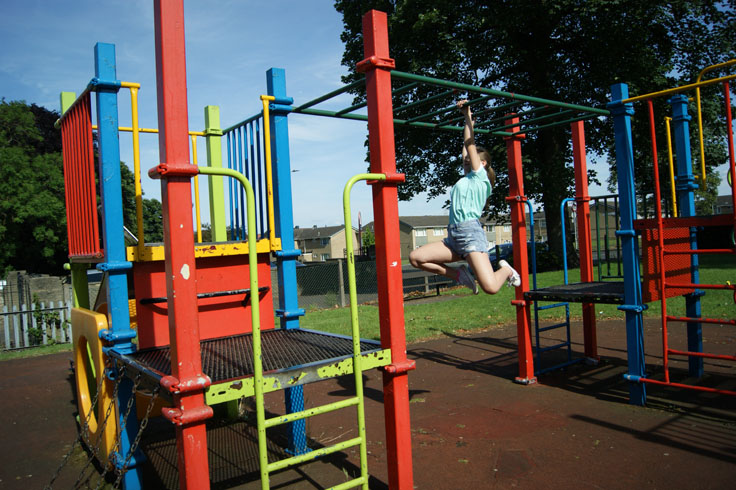 A girl on the monkey bars in a play area.